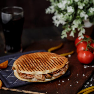 side view of chicken doner kebab in pita bread and on a wooden board and tomatoes on the table